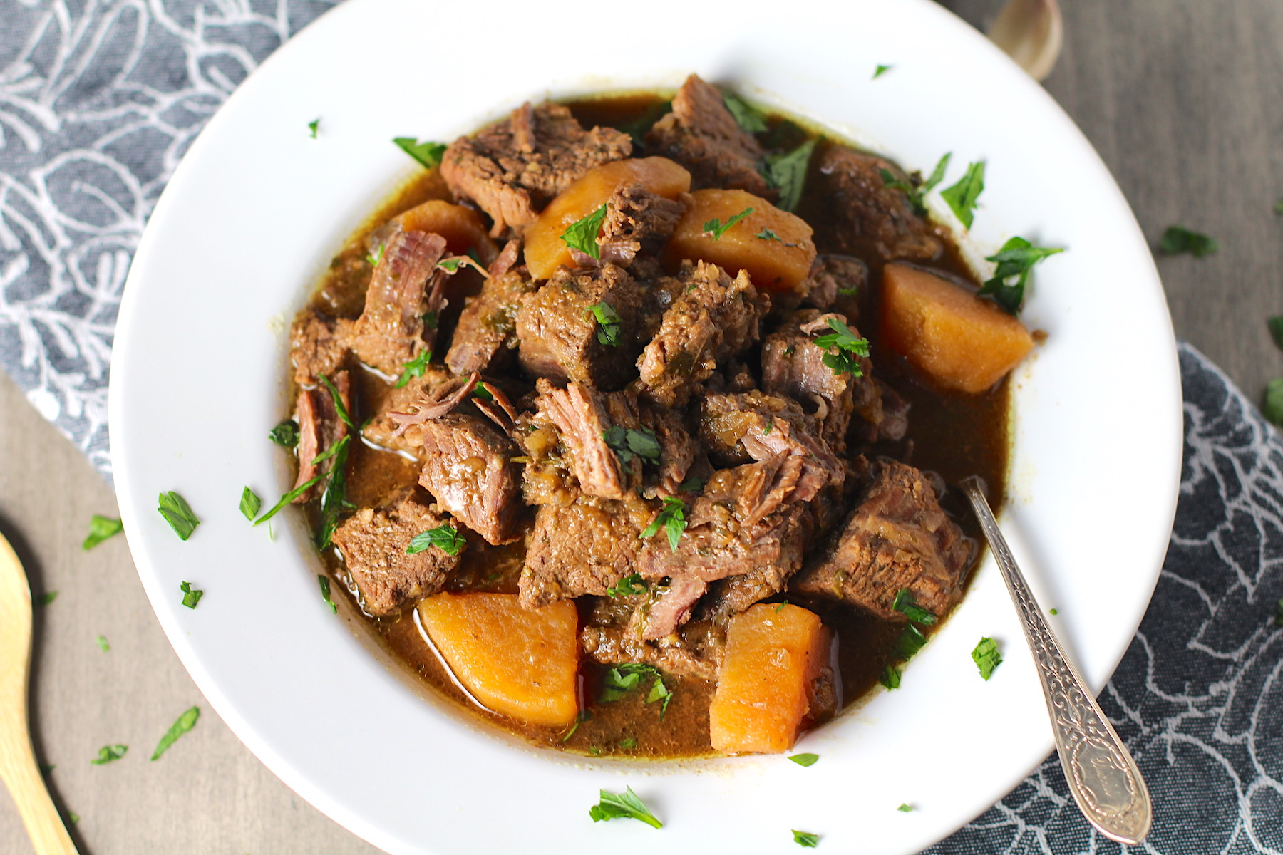 Slow Cooker Honey Garlic Beef and Potatoes in a bowl with parsley on top. It's a delicious easy dinner with tender beef cubes are cooked in the slow cooker with lots of delicious garlic, onions, and potatoes. Then honey and molasses are added for that touch of sweet.