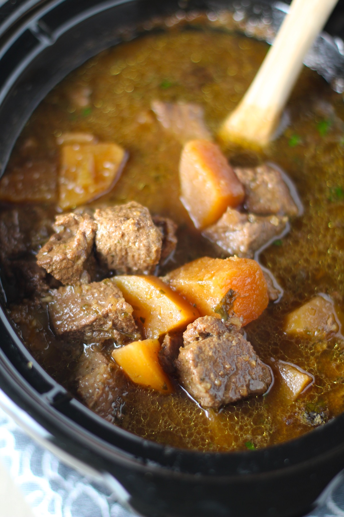 Honey Garlic Beef and Potatoes in a Slow Cooker pot with wood spoon. It's a delicious easy dinner with tender beef cubes are cooked in the slow cooker with lots of delicious garlic, onions, and potatoes. Then honey and molasses are added for that touch of sweet.