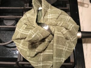 Dish towel wrapped around lid of pan for Saffron Butter Crispy Rice. Saffron brings a floral note and beautiful yellow-orange color. Added to the butter is what gives this crispy rice the buttery, crispy bottom.