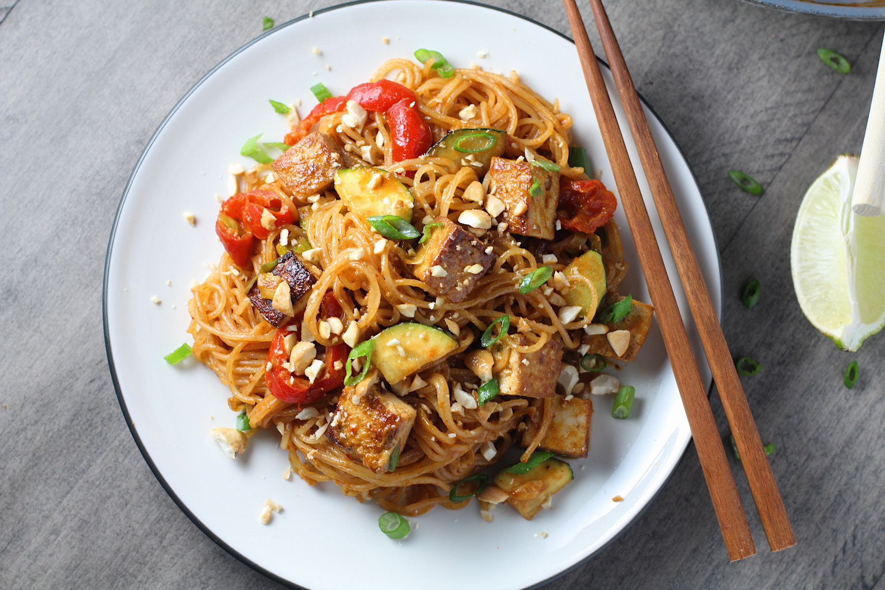 Thai Peanut Sauce Noodles with seared tofu and veggies on a plate with chopsticks.