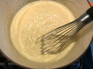Whisk mixing grits in pot for Shrimp and Grits recipe.