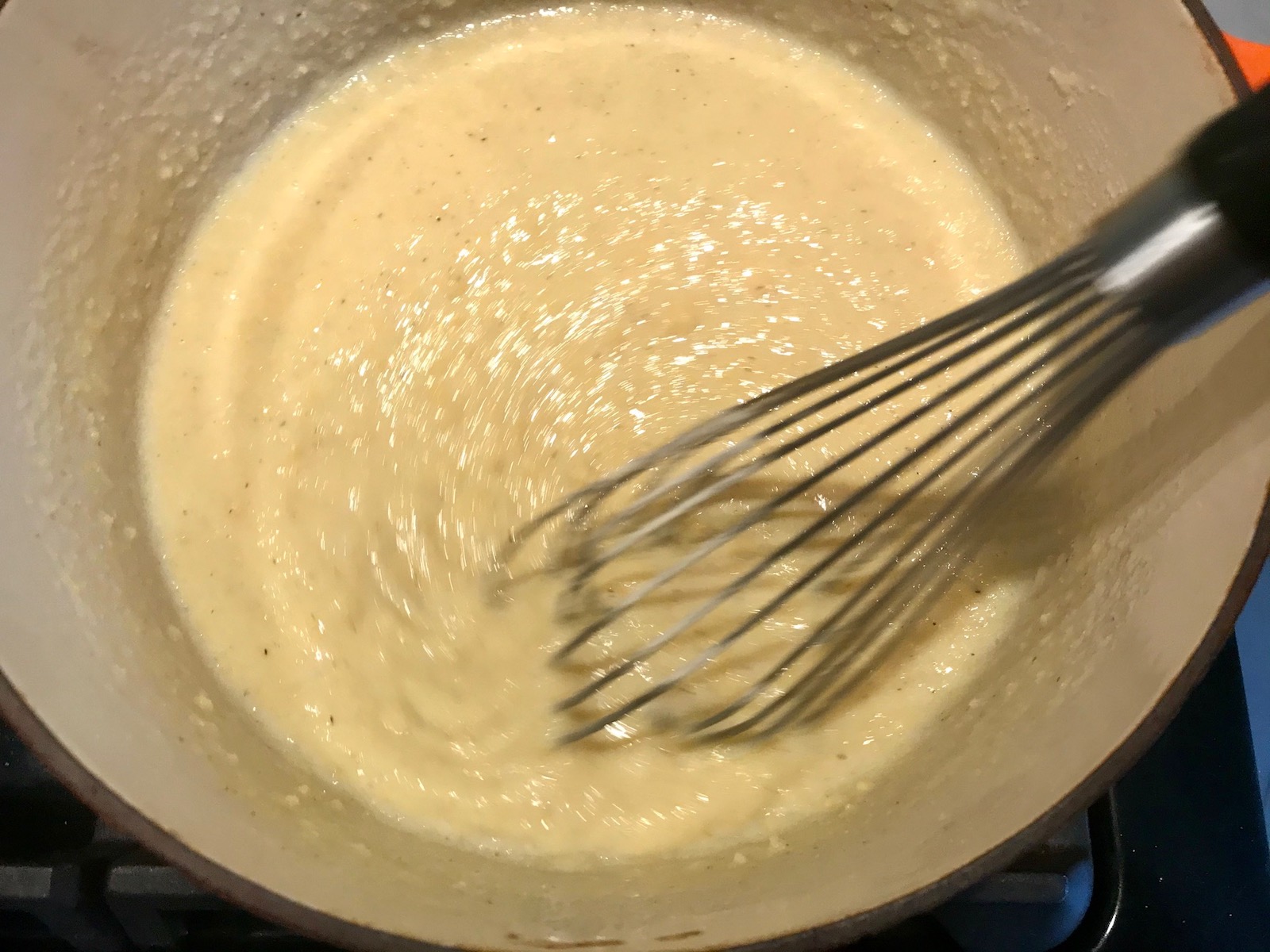 Whisk mixing grits in pot for Shrimp and Grits recipe.