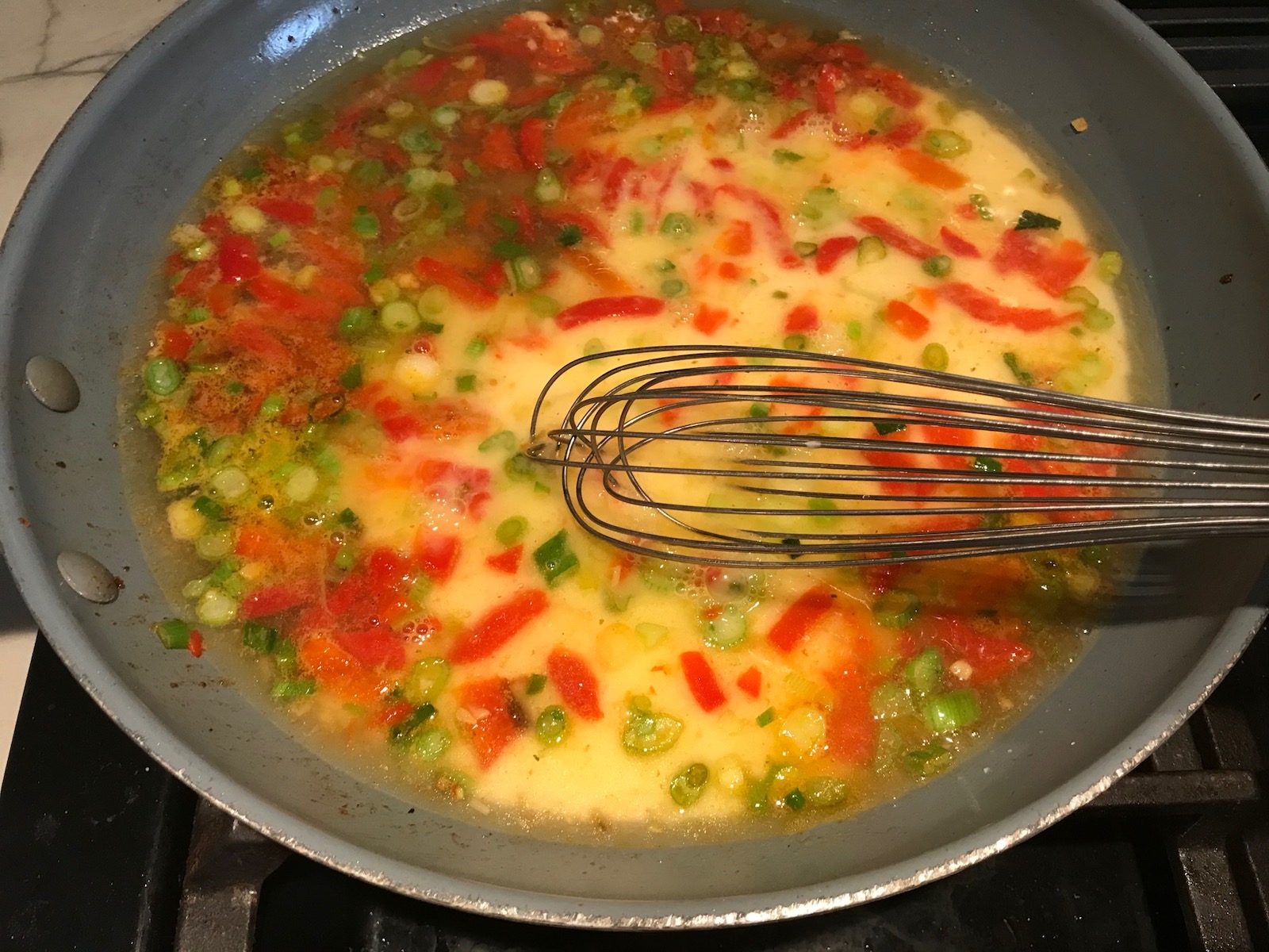 Whisk mixing the sauce in a pan for Shrimp and Grits recipe.