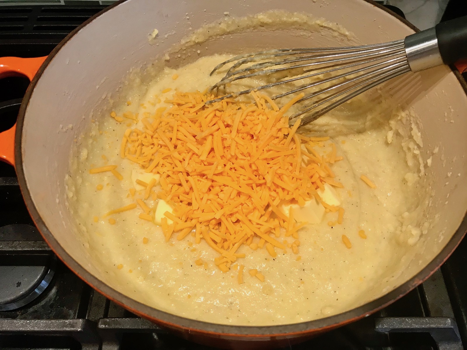 Whick mixing shredded cheddar into grits for Shrimp and Grits recipe.