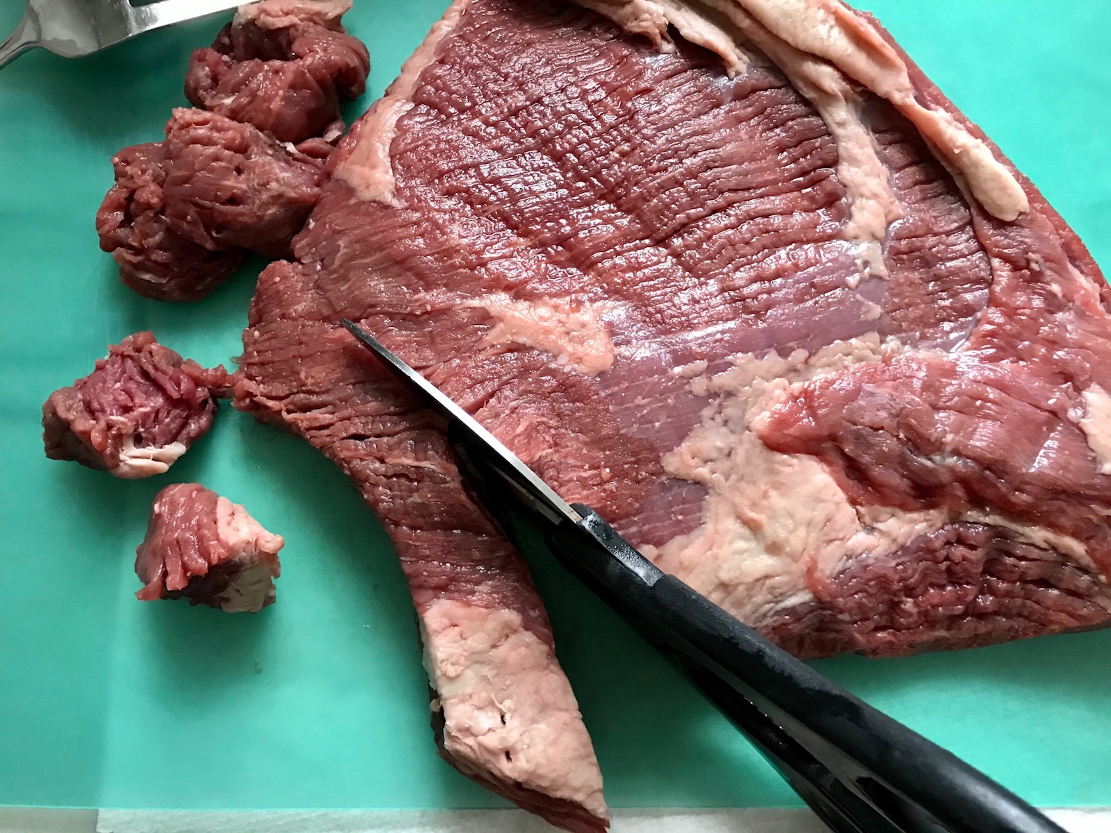 Cutting brisket with cooking shears for Honey Garlic Beef and Potatoes. It's a delicious easy dinner made in the slow cooker with tender beef cubes are cooked in the slow cooker with lots of delicious garlic, onions, and potatoes. Then honey and molasses are added for that touch of sweet.