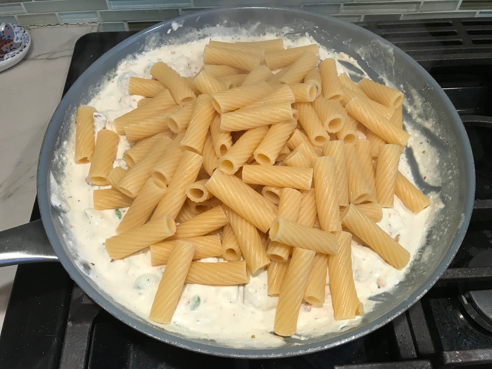Pasta added to pan with Ricotta sauce, Bacon, Mushroom Sauce on stove. It's creamy, rich, decadent, comforting, and downright delicious!