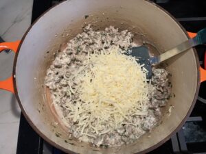 Cheese added to ground beef and herbs cooking in a pot for White Lasagna Recipe with Zucchini and Ground Beef