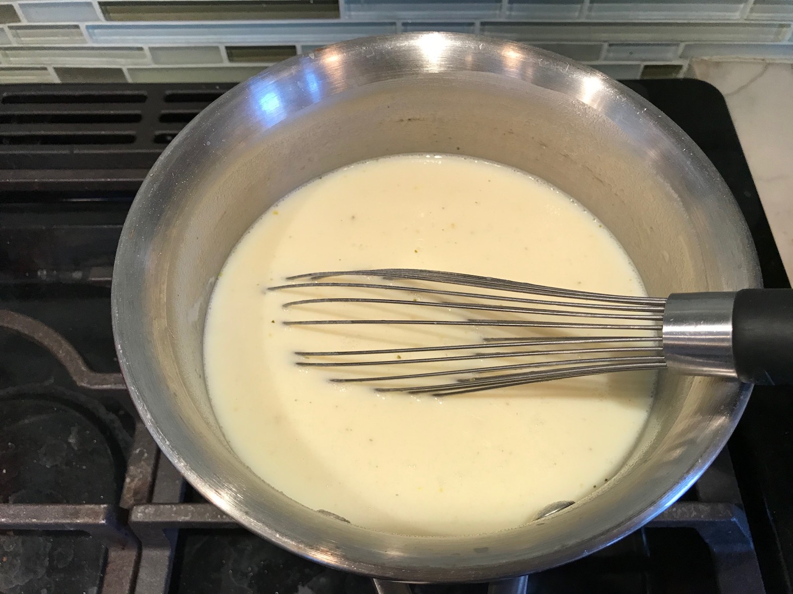 Whisk mixing white sauce in a pot for White Lasagna Recipe with Zucchini and Ground Beef