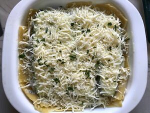 Shredded cheese and parsley on top of assembled White Lasagna Recipe with Zucchini and Ground Beef