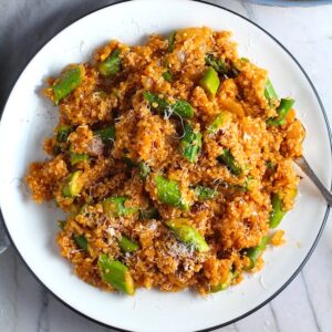 Asparagus and Tomato Quinoa Risotto with parmesan on top on a plate with fork.