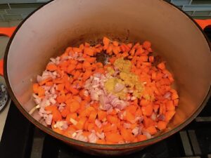 Diced carrots, onions, garlic, and ginger cooking in pot for Golden Carrot Ginger Soup Recipe.