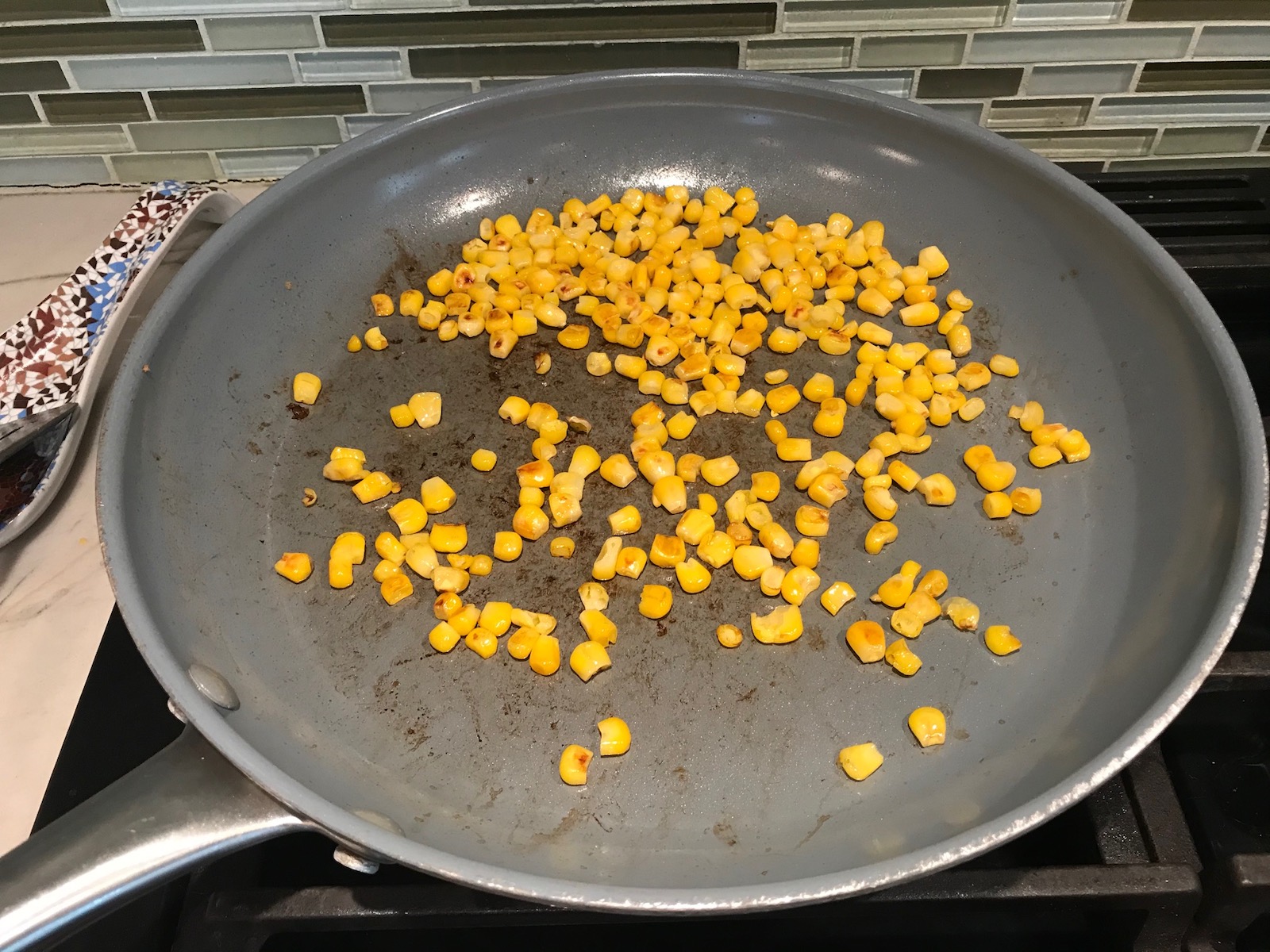 Corn in pan getting seared for Taco Quinoa Bowl with Ground Beef, corn, cotija cheese, tomatoes, fresh cilantro, and cilantro lime crema