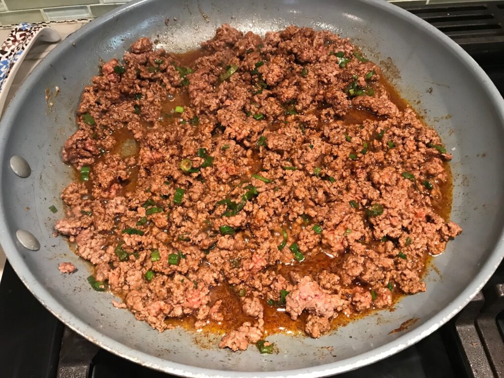 Cooked ground beef in pan for Taco Quinoa Bowl with Ground Beef, corn, cotija cheese, tomatoes, fresh cilantro, and cilantro lime crema