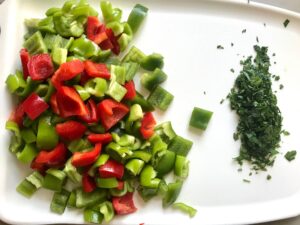 Chopped green and red bell peppers and cilantro on a cutting board for Tex Mex Unstuffed Peppers with Ground Chicken. Juicy Sweet Bell Peppers are chopped up and cooked with the Tex Mex style ground chicken, tomatoes, Mexican seasonings, cheese, rice and corn tortillas.