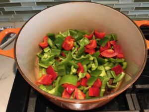 Chopped green and red bell peppers cooking in pot for Tex Mex Unstuffed Peppers with Ground Chicken. Juicy Sweet Bell Peppers are chopped up and cooked with the Tex Mex style ground chicken, tomatoes, Mexican seasonings, cheese, rice and corn tortillas.