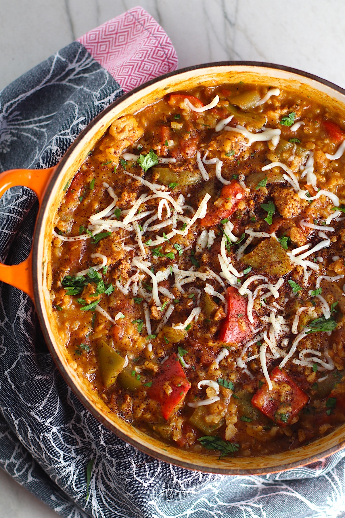 Pot of Tex Mex Unstuffed Peppers with Ground Chicken and cheese sprinkled on top op. Juicy Sweet Bell Peppers are chopped up and cooked with the Tex Mex style ground chicken, tomatoes, Mexican seasonings, cheese, rice and corn tortillas.