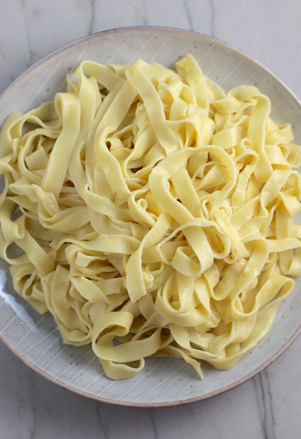 Easy Homemade Pasta, plain Fettuccine, on a plate on counter.