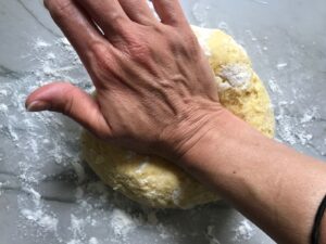 Hand kneading dough on floured counter for Easy Homemade Pasta recipe.