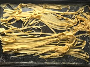 Easy Homemade Pasta plain Fettuccine on a sheet pan with cornmeal.
