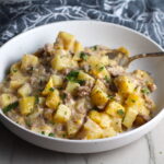 Cheesy Hamburger Potato Casserole in a bowl with a spoon. It's an easy, yummy, and cozy weeknight family dinner. 