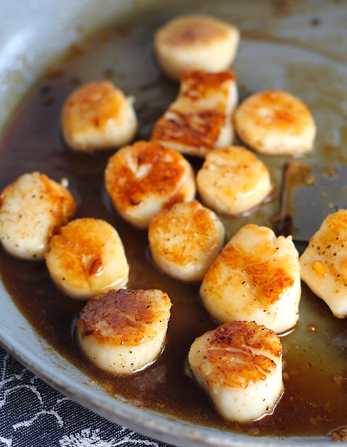 Glazed Pan Seared Scallops with Garlic and Honey in a pan with spatula.