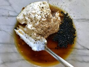 Mayonnaise, teriyaki sauce, sesame seeds, salt, and pepper in a bowl unmixed for Teriyaki Chicken Salad..