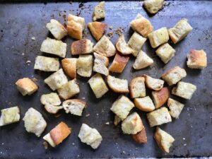 Toasted bread cubes on a sheet pan for this Chicken Panzanella Salad Recipe. It's absolutely delicious.