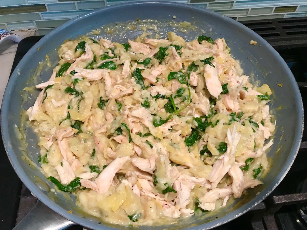 Spinach Artichoke Grilled Chicken Pita filling in a large pan on stove for stuffing into pitas and then grilling.