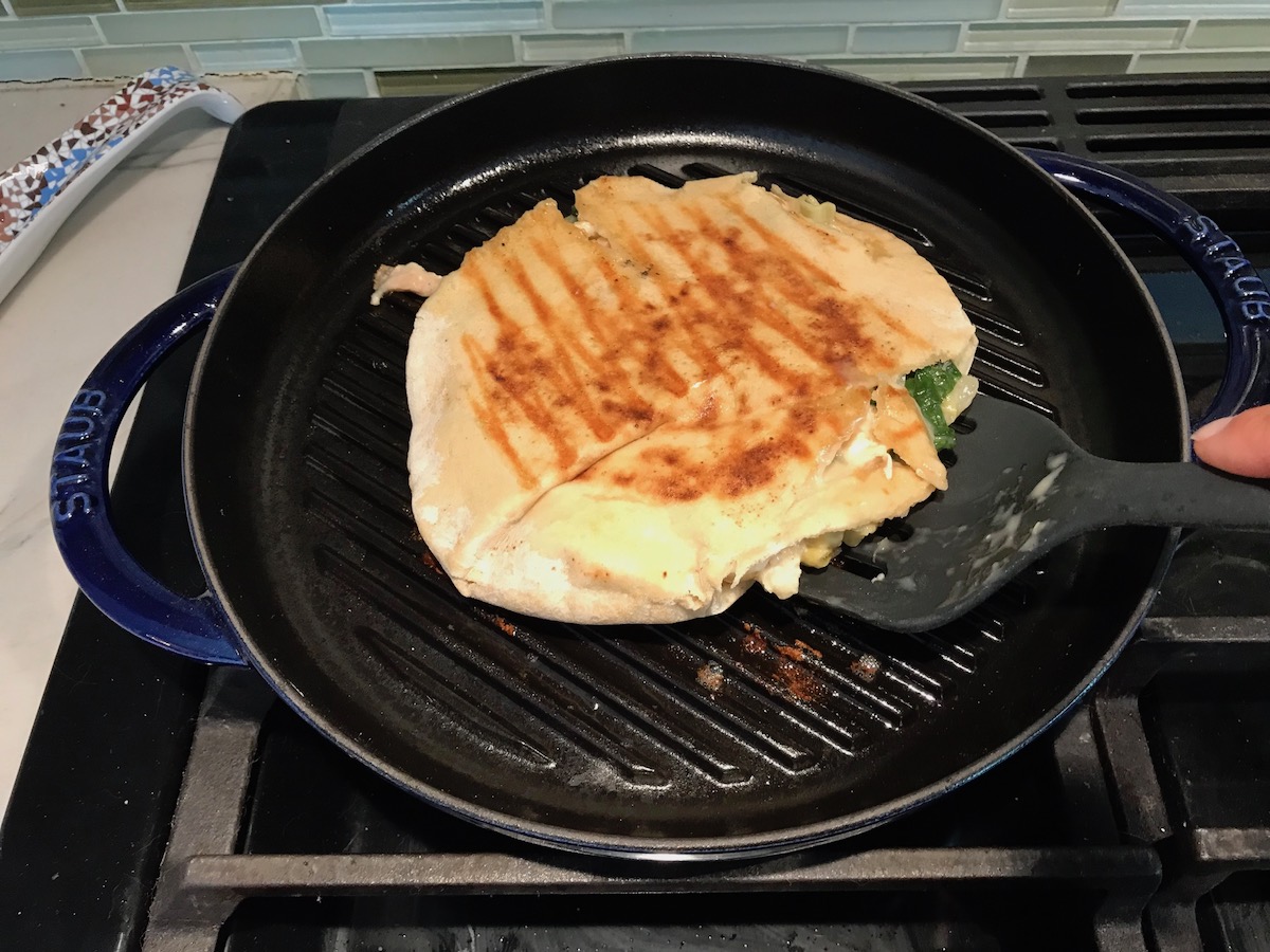 Spinach Artichoke Grilled Chicken Pita grilling on a round grill pan on the stove.