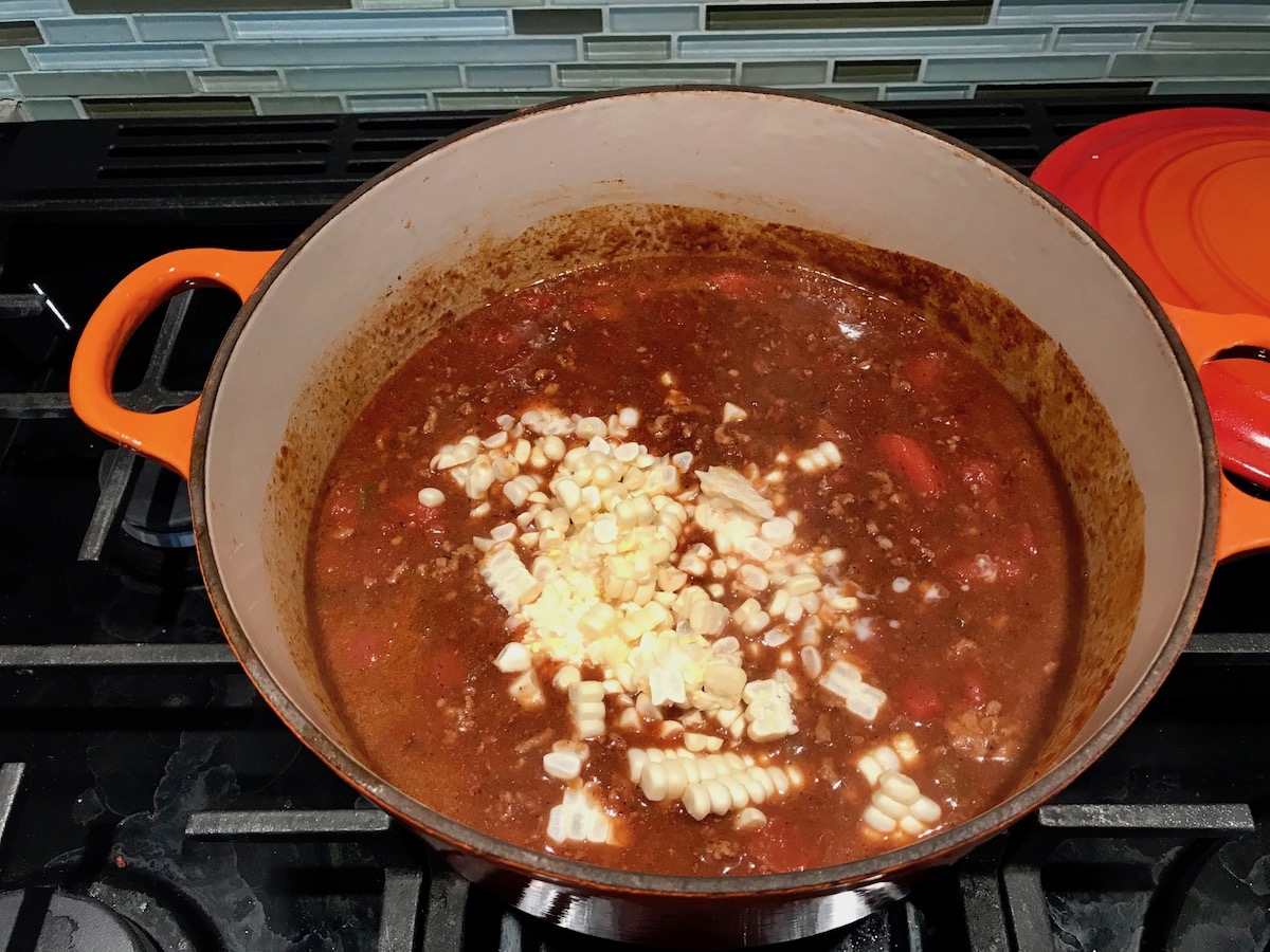 Corn kernels added to pot of ground beef and tomato-chile sauce for Southwestern Pasta with Ground Beef and Corn and breadcrumbs. The sauce is thick and hearty with ground beef, sweet corn kernels, chunky tomatoes, chipotle peppers in adobo, green chiles, parmesan cheese, and lots of smokey and spicy seasonings.