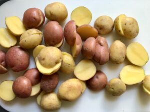 Halved red and gold creamer potatoes on cutting board for Sage Butter Potatoes.