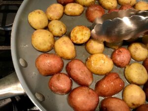 Halved red and gold creamer potatoes on cutting board for Sage Butter Potatoes.