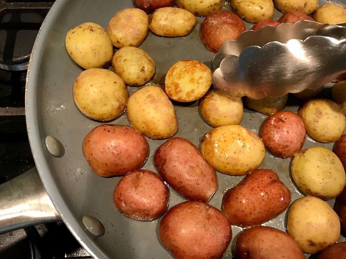 Halved red and gold creamer potatoes on cutting board for Sage Butter Potatoes.