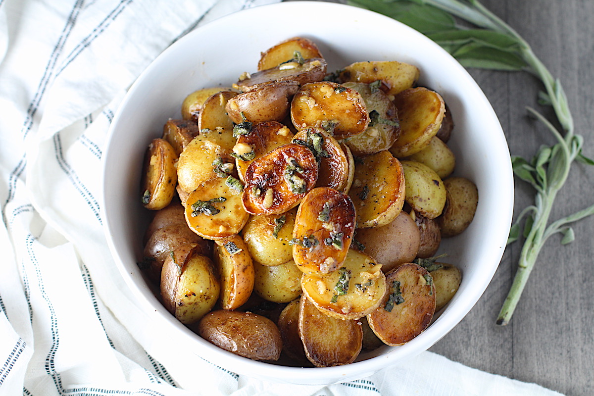Crispy browned Sage Butter Potatoes in a bowl with garlic, sage butter glistening on top.