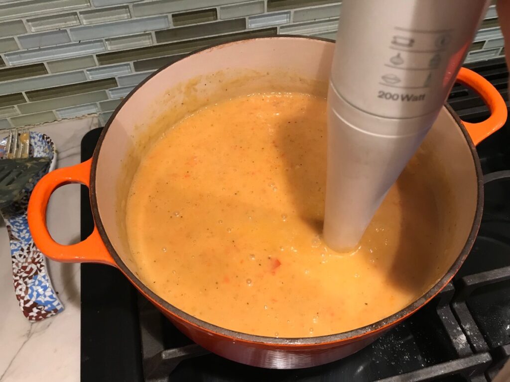 Immersion blender blending soup in pot for Red Pepper and Lentil Soup. This is an easy and hearty lunch or dinner! It comes together in just 40 minutes.