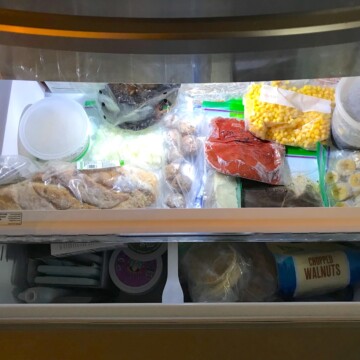 Pull-out drawer freezer filled with frozen veggies, bread, sauce, bananas, corn, and more for post 'Can you freeze pulled pork'.