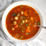 Vegetable Garbanzo Soup recipe in a bowl with a spoon on a counter with a napkin. It's slightly creamy and filled with flavor and texture! It's super easy to make ahead and enjoy during the week.