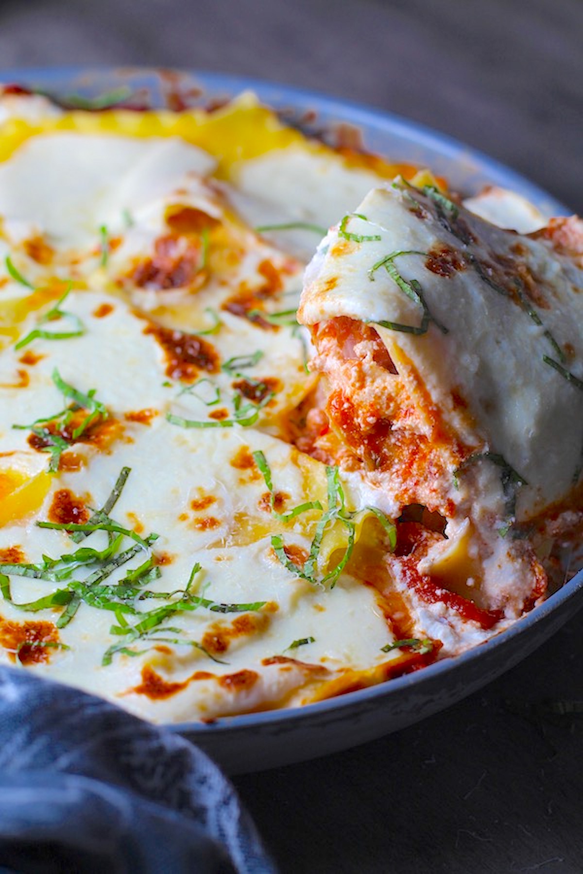 Angle shot of No-Bake Lasagna in skillet with spatula scooping a piece out. It cooks in a skillet or frying pan on the stovetop to save time!
