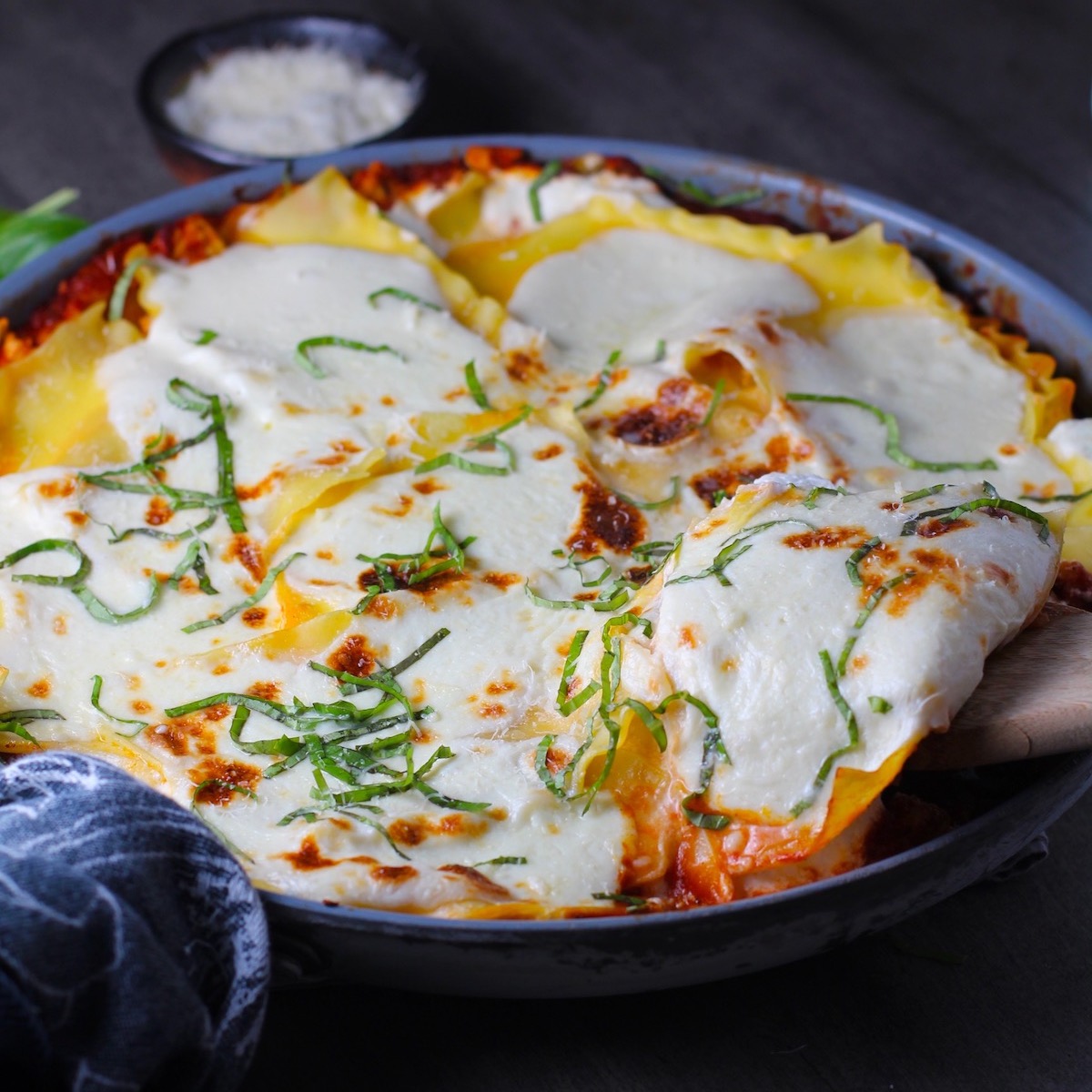 Angle shot of No-Bake Lasagna in skillet with spatula scooping a piece out. It cooks in a skillet or frying pan on the stovetop to save time!
