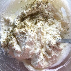 Ricotta filling recipe in bowl being mixed with parmesan and italian seasonings.