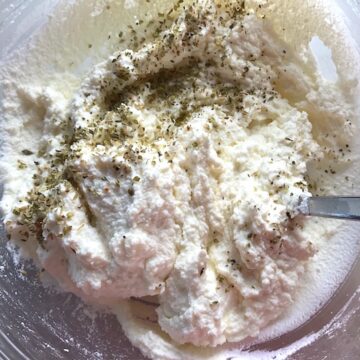 Ricotta filling recipe in bowl being mixed with parmesan and italian seasonings.