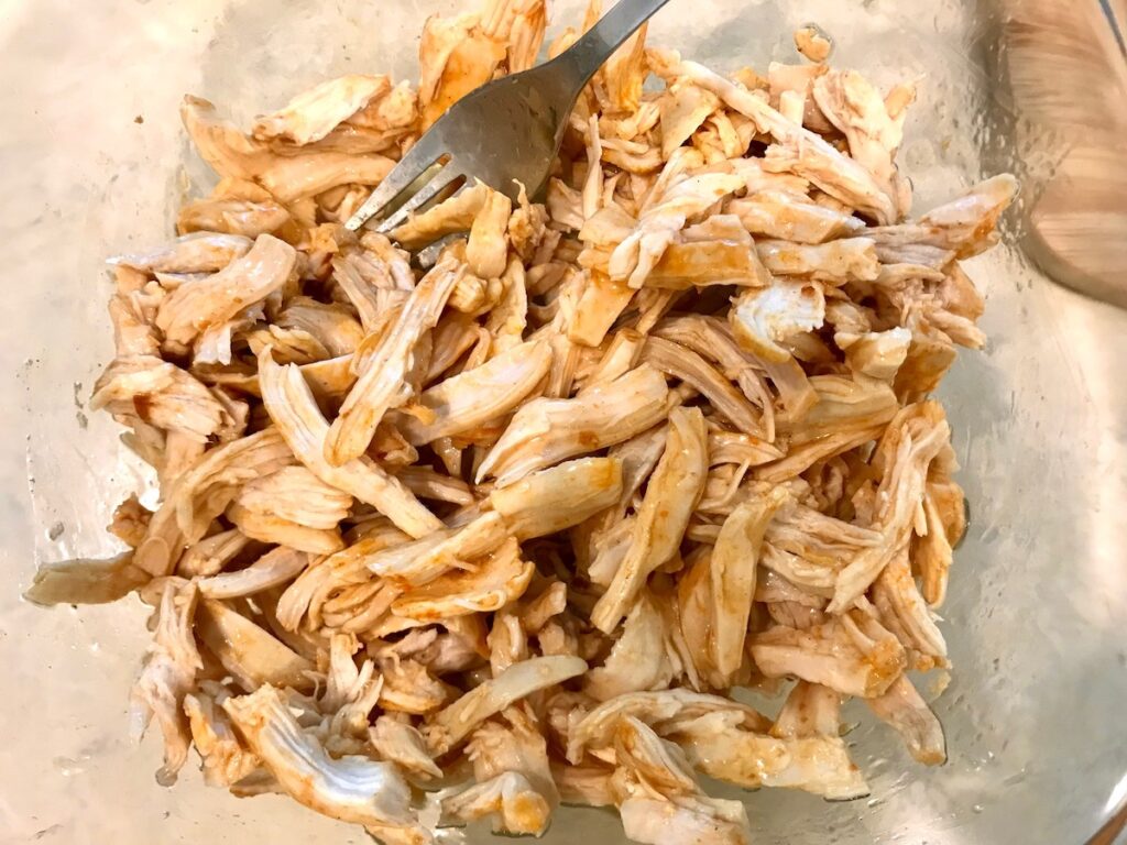 Shredded chicken coated with buffalo sauce for Buffalo Chicken Dip with greek yogurt