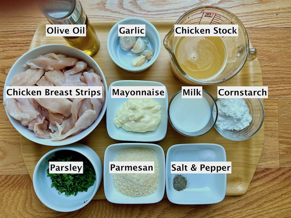 All ingredients prepared and measured in bowls on a wood counter for White Sauce Chicken Pasta recipe.