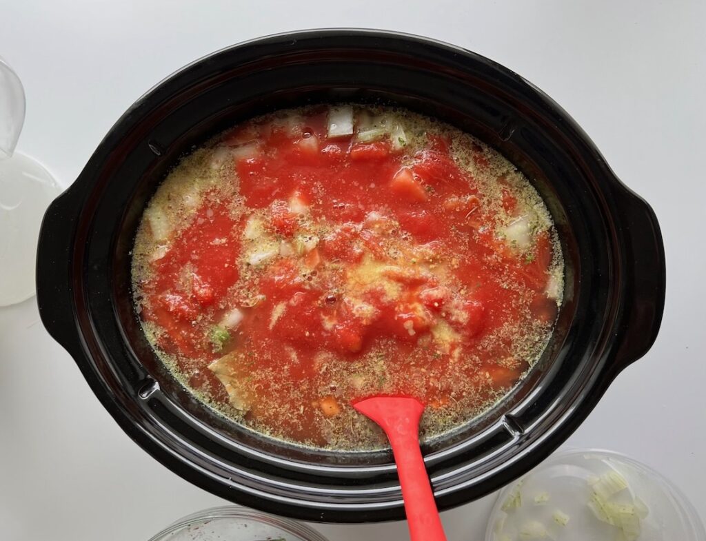 Diced tomatoes and broth added to the ground beef and vegetables in a slow cooker insert for Ground Beef Vegetable Soup Recipe. It's a perfect fall meal that's comforting, hearty, and delicious with loads of veggies!