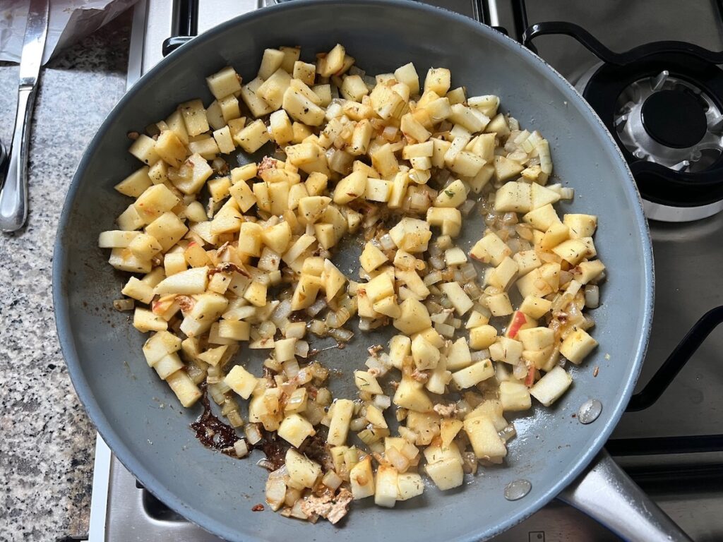 Onions and apples cooking in butter in a pan for Pork Normandy recipe.