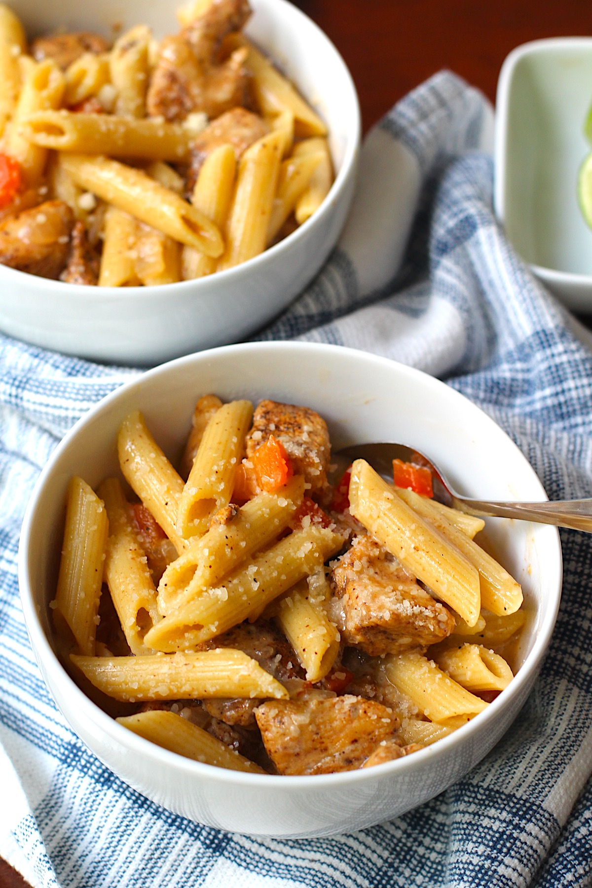 Two bowls of Chipotle Chicken Pasta with penne pasta and a spoon in the font bowl.