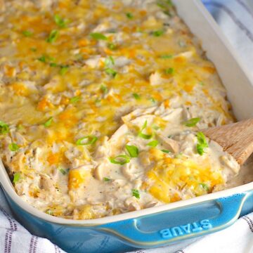 Chicken Hashbrown Casserole Recipe in a casserole dish on a towel with wooden spatula in it.