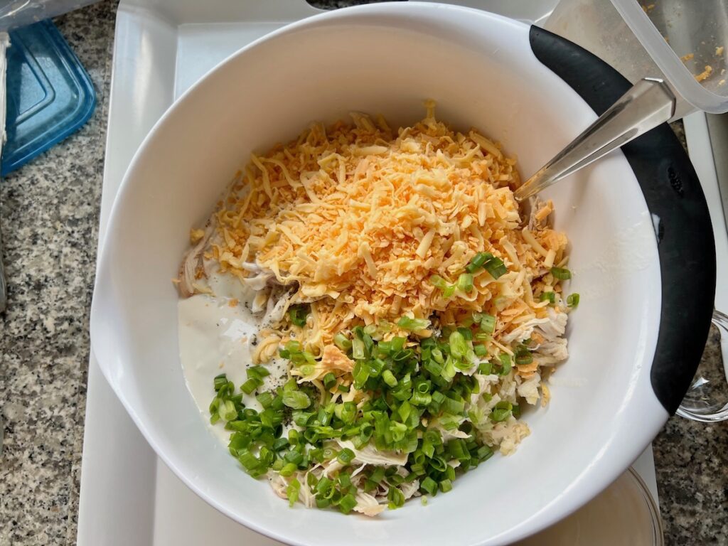 Hashbrowns, chicken, cheese, scallions, and cream cheese sauce for Chicken Hashbrown Casserole recipe.