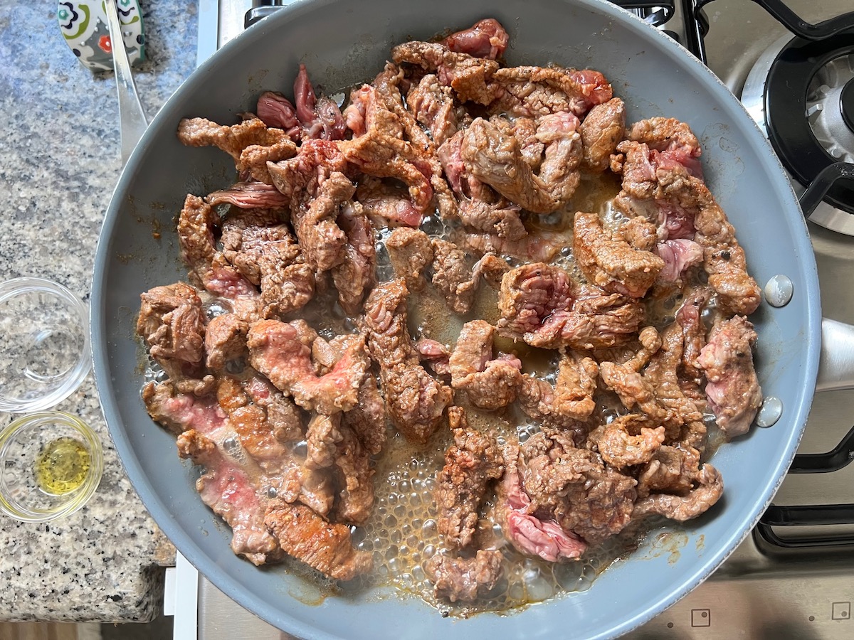 Flank steak cooking in a skillet for Philly Cheesesteak casserole recipe with Steak.