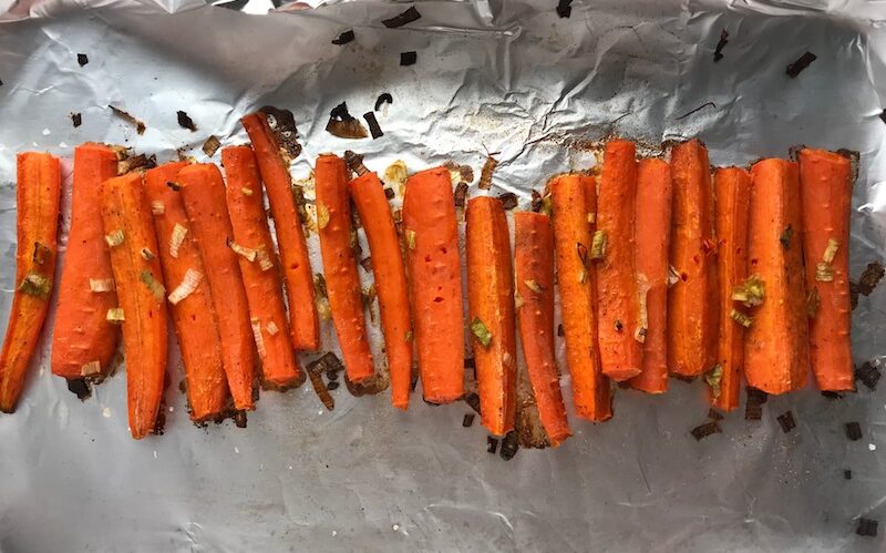 Roasted Carrots on a pan with scallions. Roasted Carrots with smoky cumin and scallions, then topped with Avocado Crema are such a delicious and quick side dish for dinner. Roasting brings out the natural sugar in the carrots, so they get a sweet caramelization with the salty and smoky flavors. The Avocado crema gives creamy and silky balance.